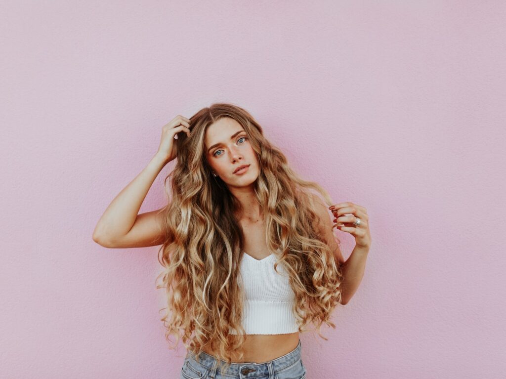 woman standing next to pink wall while scratching her head