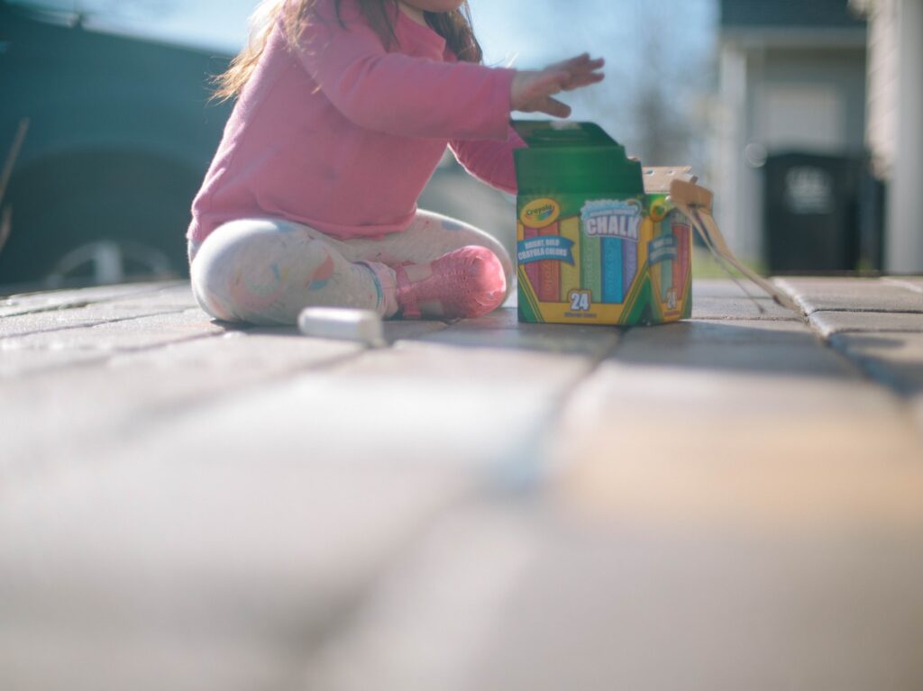 girl sitting beside box of chalk