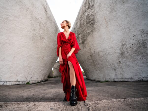 woman in red long sleeve dress and black boots standing beside gray concrete wall during daytime